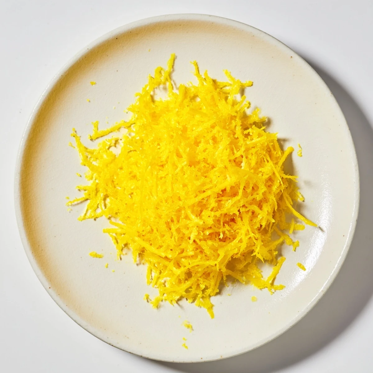 Freshly grated lemon peel, vibrant yellow zest bursting with citrus fragrance for your cooking.