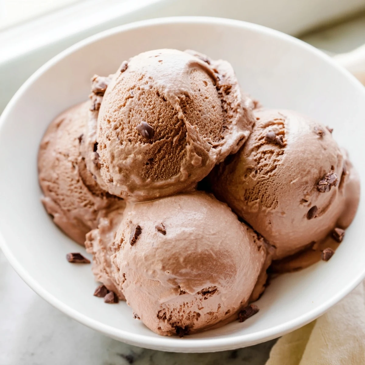 Rich, dark chocolate ice cream swirled in a bowl, a decadent dessert to cool you down.