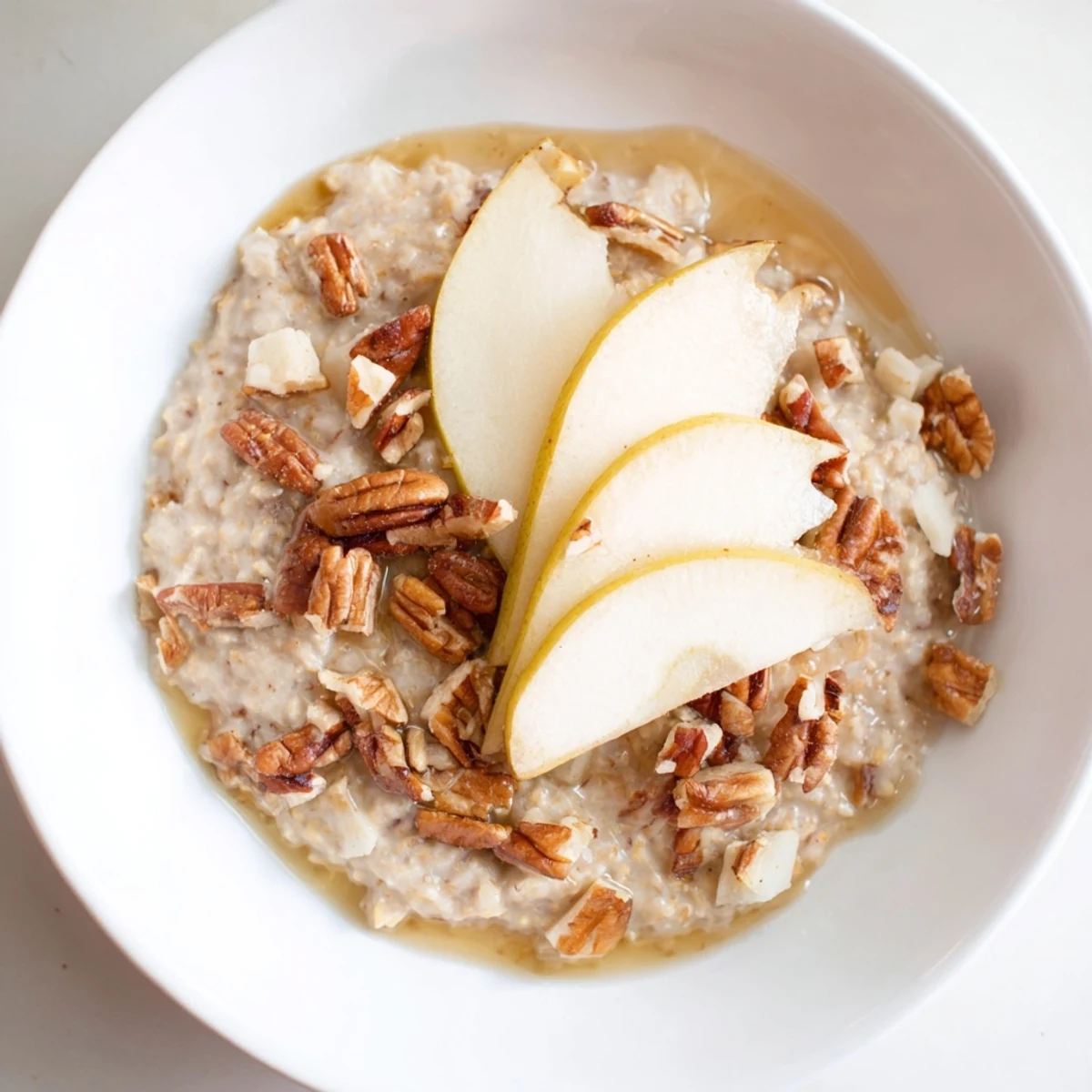 Creamy Hearty Pear and Spice Coconut Milk Porridge topped with pecans and fresh pear slices.