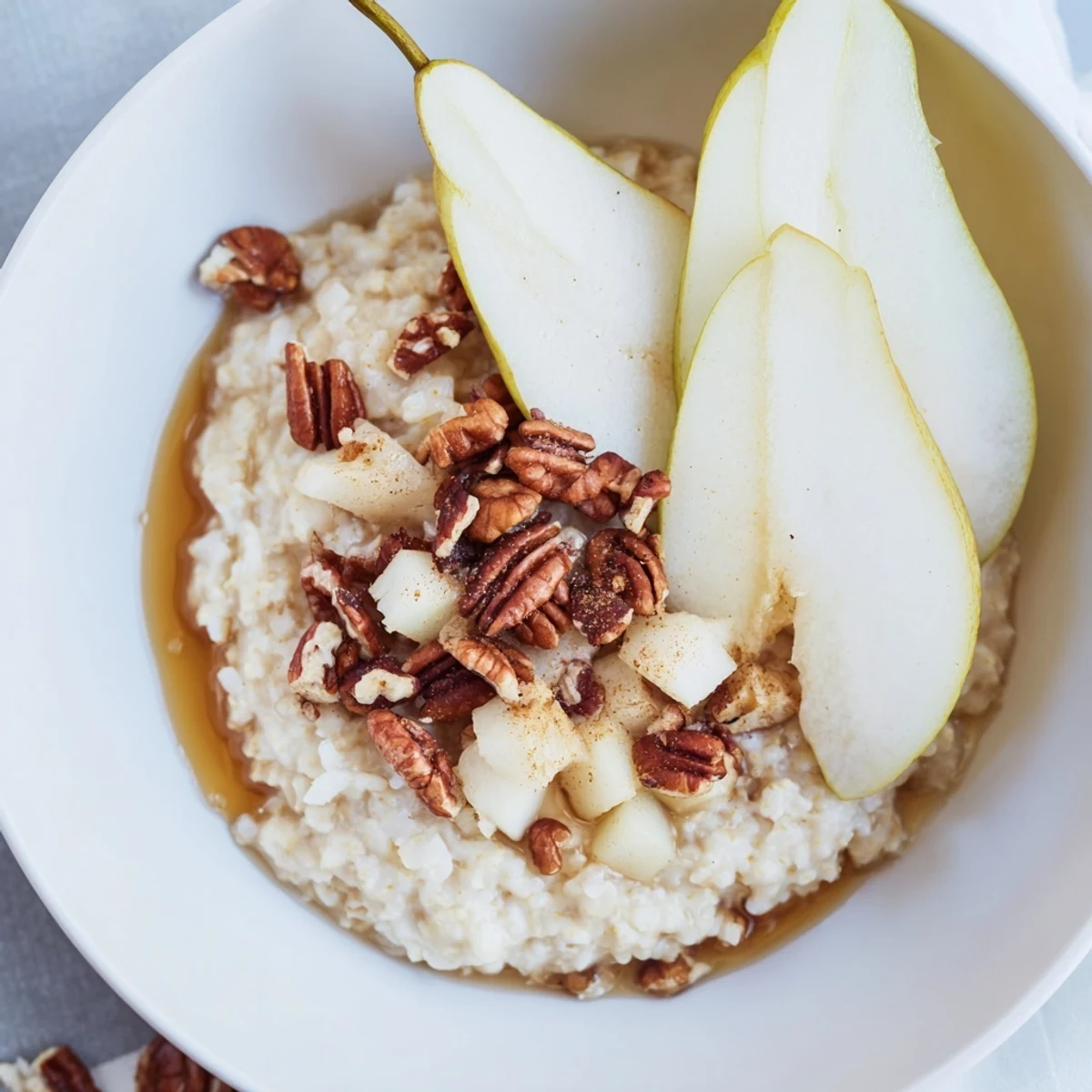 Warm, spiced Hearty Pear and Spice Coconut Milk Porridge with a drizzle of maple syrup, ready to eat.