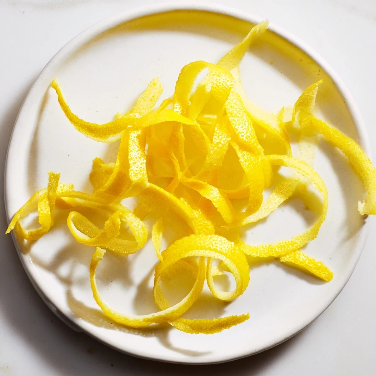 Peeling a lemon with a vegetable peeler: revealing bright yellow zest for vibrant dish flavoring.