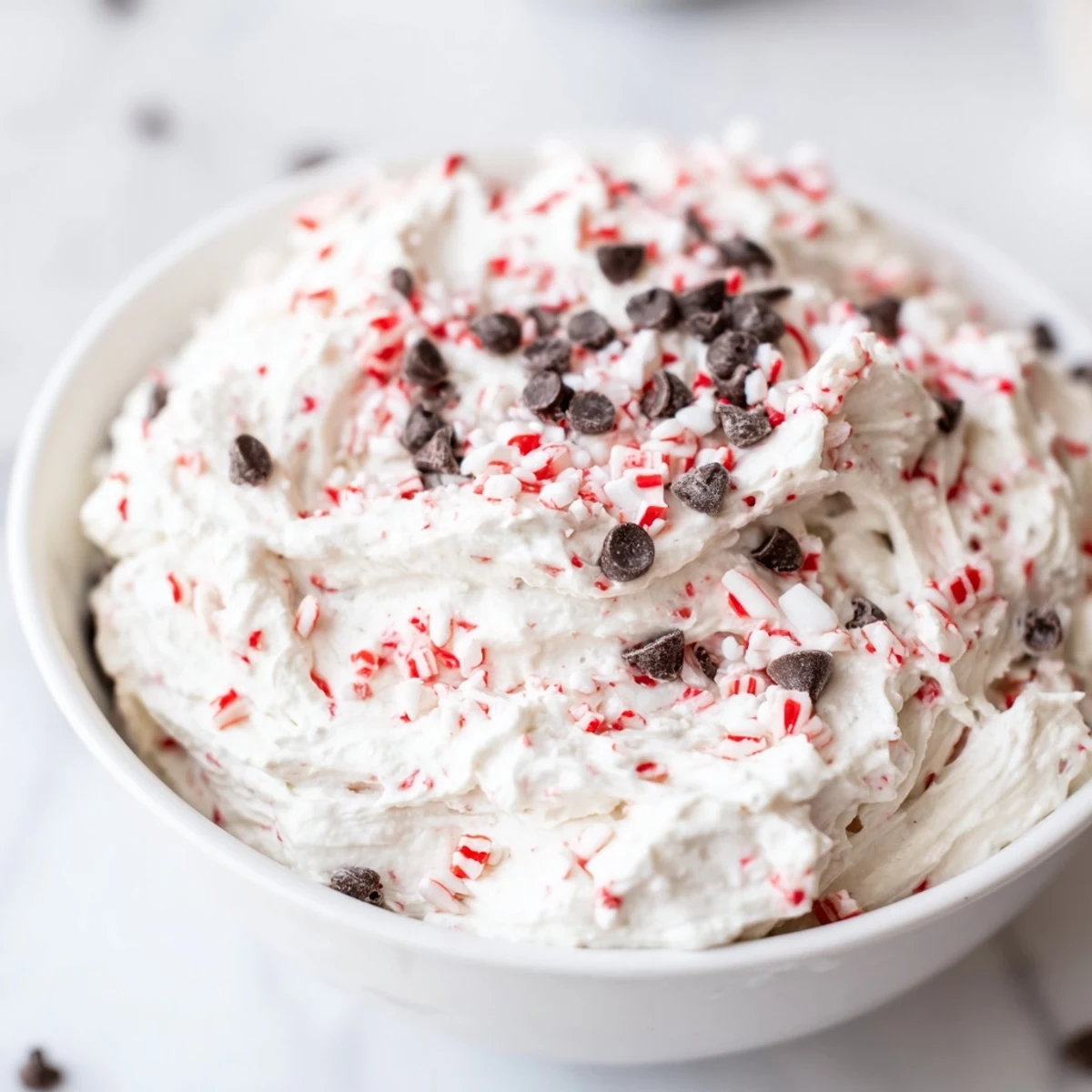 Festive bowl of Peppermint Fluff Dip, a smooth and airy dessert served at a holiday party.