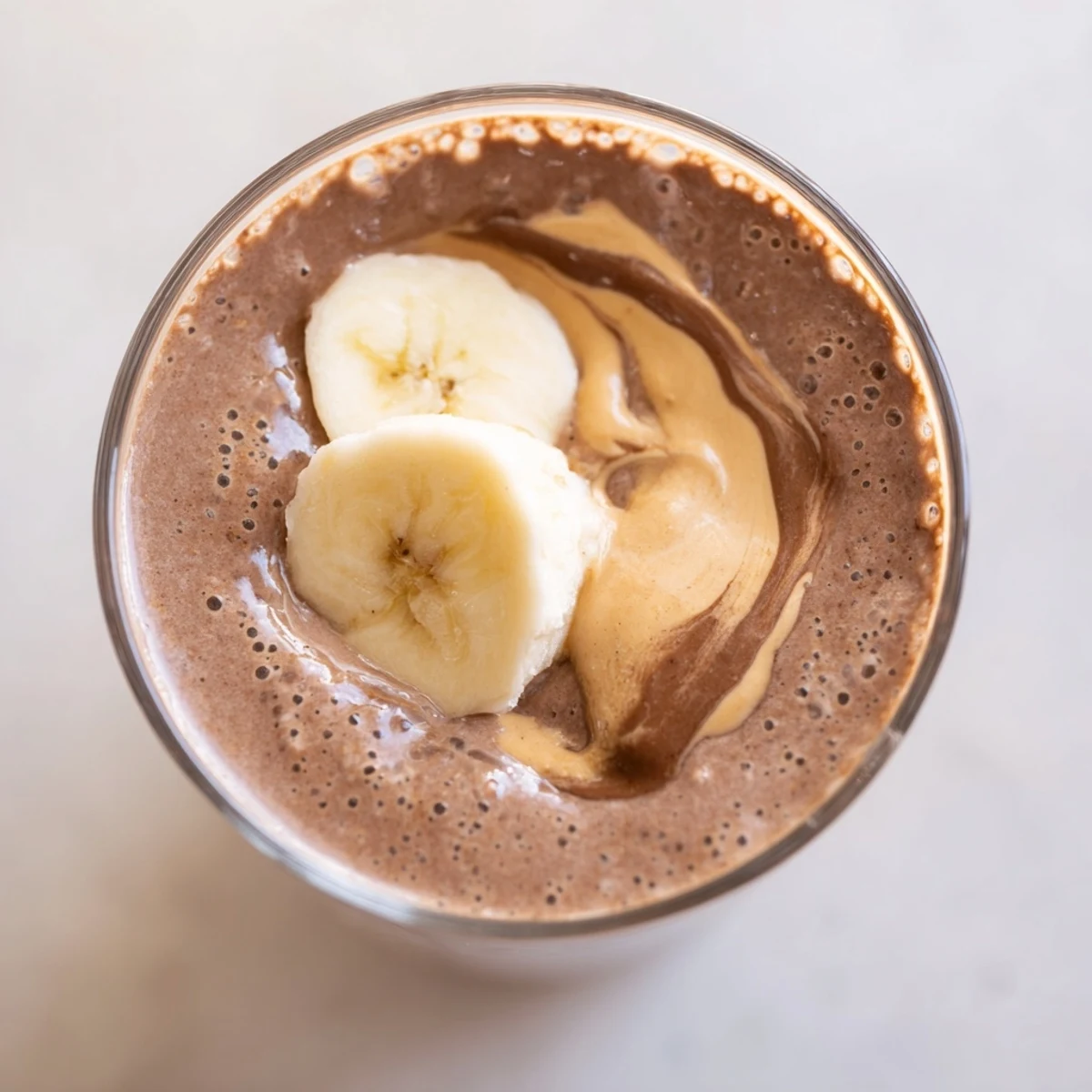 Un smoothie onctueux au chocolat, cacahuète et banane, servi dans un verre haut.