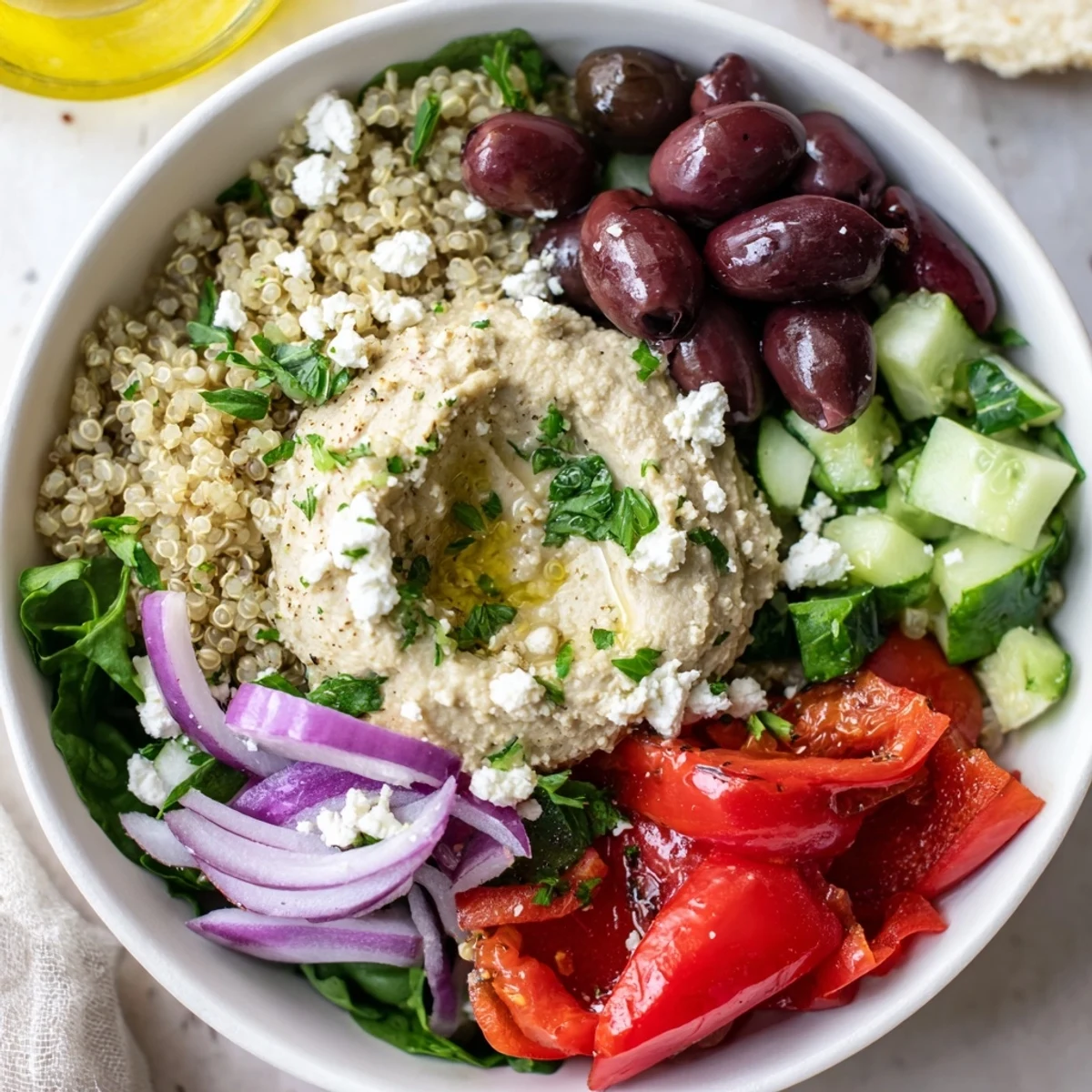 Bowl Méditerranéen au Quinoa avec Hummus, servit avec tomates cerises et poivrons grillés.