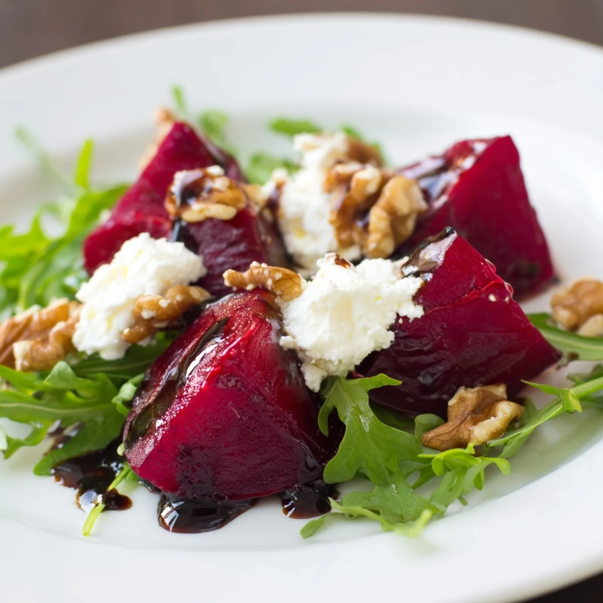 Salade de betteraves rôties et noix avec roquette, quartiers de betteraves tendres, noix et oignons rouges sur fond de roquette, présentation appétissante.