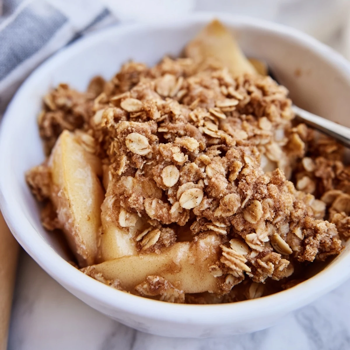Tarte aux pommes cuites au four avec un garniture de granola croustillante et dorée, servie chaude.