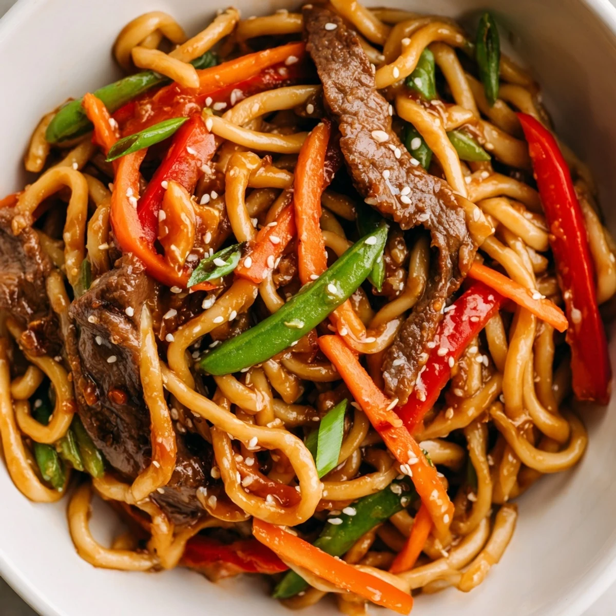 Spicy Beef Stir Fry with Udon Noodles tossed with crisp veggies and steam rising from the hot wok.