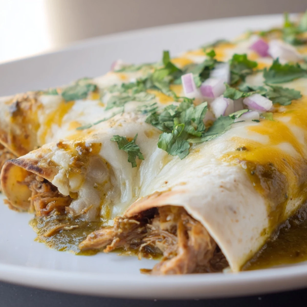 Perfectly baked Beef Enchiladas with Green Chili Sauce, finished with cilantro and fresh lime wedges.