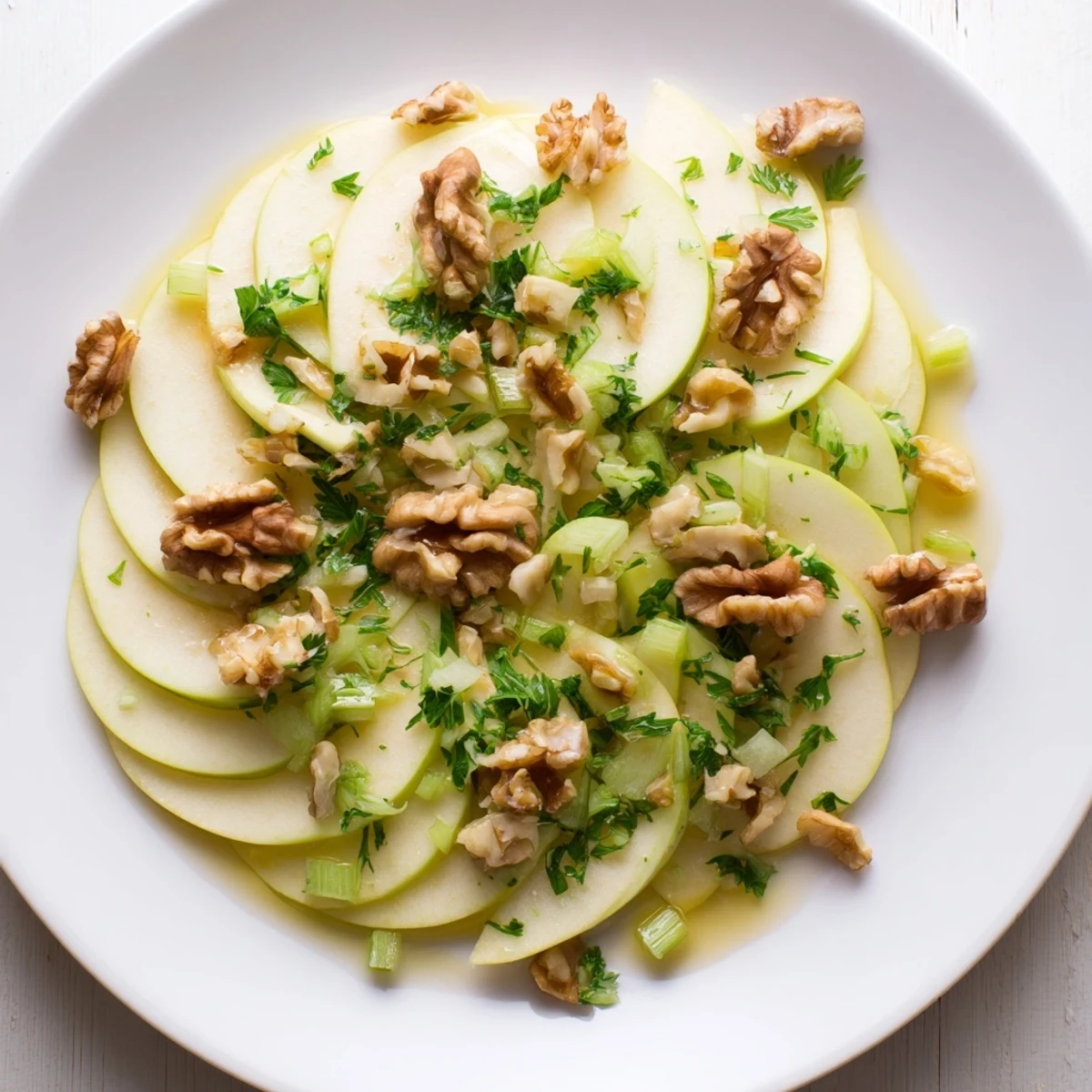 Salade aux pommes, céleri et noix, garnie de persil frais et d'huile d'olive extra vierge.