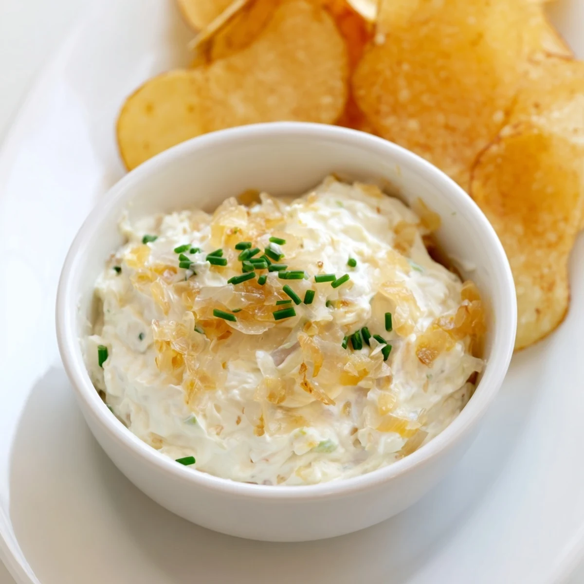 Freshly fried russet potato chips served with a savory, chilled onion dip for a classic American snack.