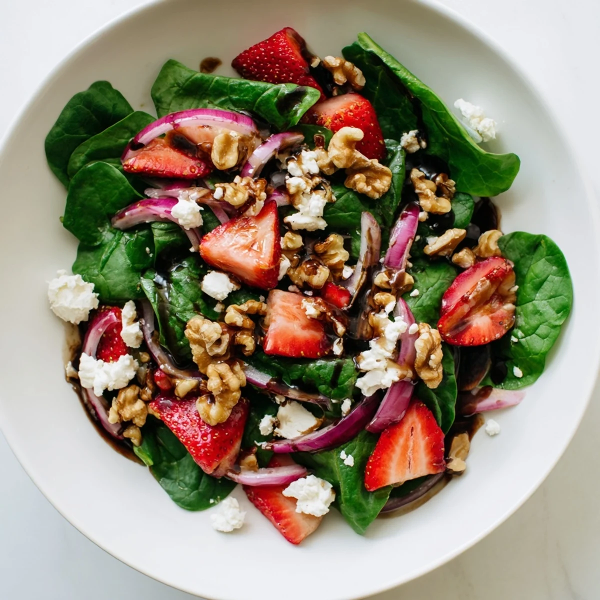 Une portion savoureuse de salade aux épinards et fraises, où la douceur des fruits se marie à la saveur terreuse des noix et au tangage du vinaigre.