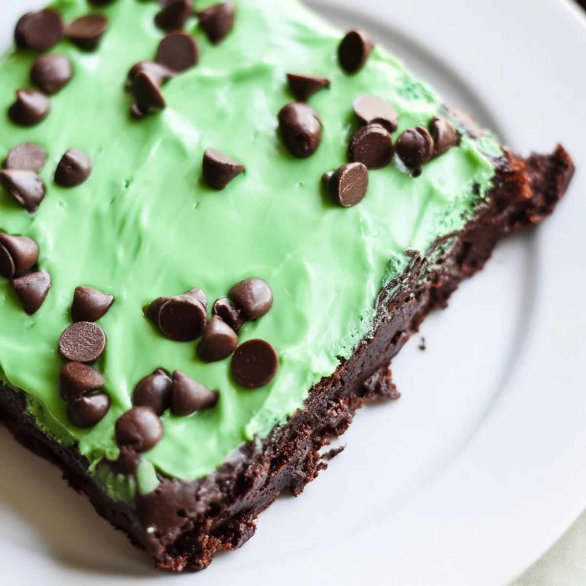 Un lot de Green Mint Brownies with Chocolate Chips posé sur une planche en bois, avec une texture moelleuse et des éclats de chocolat fondu.