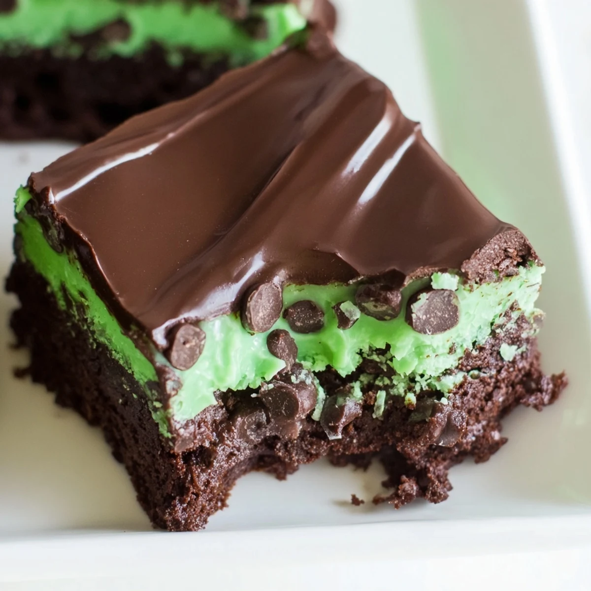 Fudgy Green Mint Brownies with Chocolate Chips glistening with rich chocolate ganache, cut into squares.