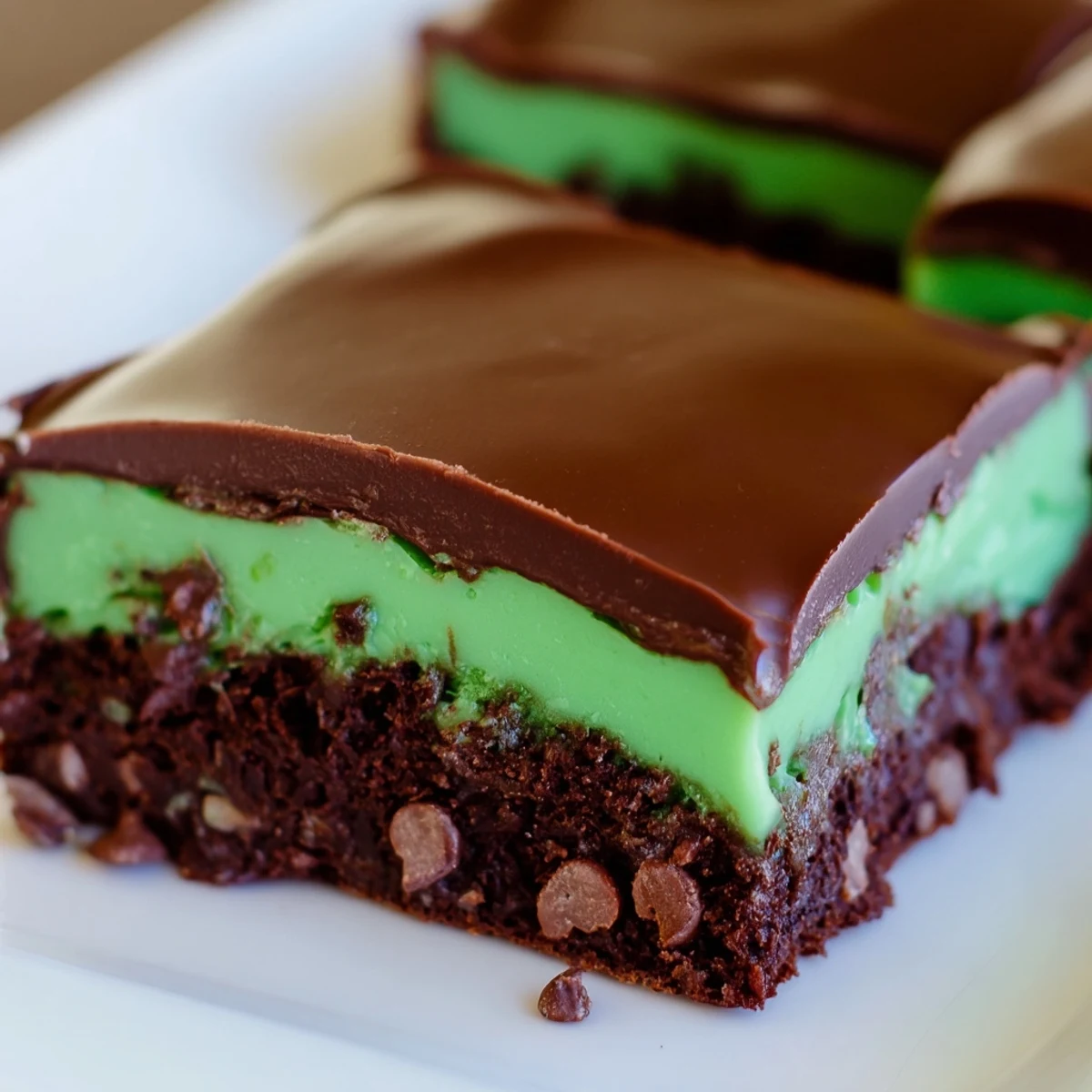 Decadent Green Mint Brownies with Chocolate Chips layered with vibrant mint frosting on a wooden board.
