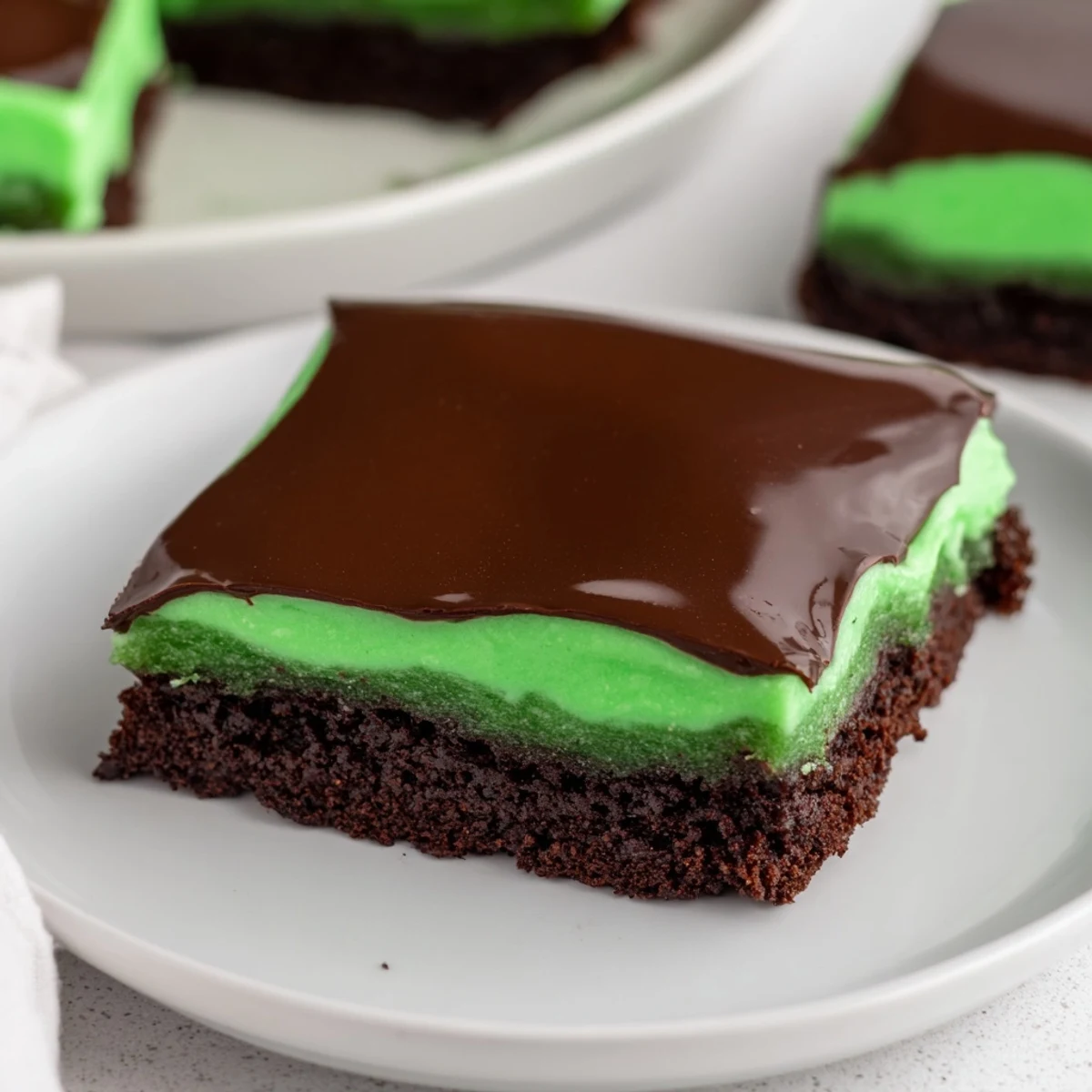 Decadent Green Mint Brownies on a plate with mint garnish, showcasing moist crumb and refreshing chocolate mint flavors.