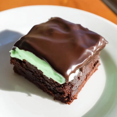 Des Green Mint Brownies appétissants présentés sur une assiette, avec une texture riche et fumée.