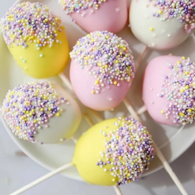 Handheld Easter Egg Cake Pops with Sprinkles on wooden lollipop sticks, decorated with bright sprinkles, perfect finger-food treats for family celebrations and Easter brunch.